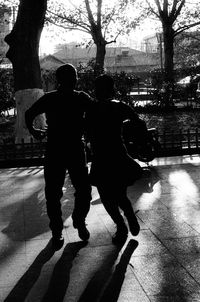 Rear view of men walking on footpath in city