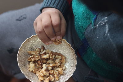 Midsection of boy having walnut in bowl