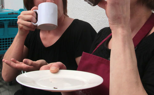 Midsection of man holding coffee cup on table