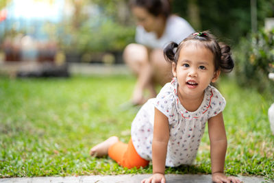 Girl crawling on grass in yard 