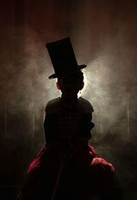 Man with arms outstretched standing on illuminated lamp at night