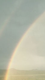 Scenic view of rainbow over mountain against sky