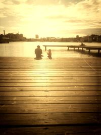 Pier over river against sky during sunset