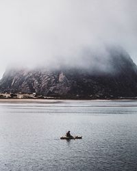 Man sailing on lake against sky