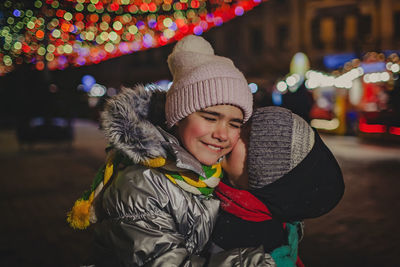 Cute sibling embracing at night outdoors