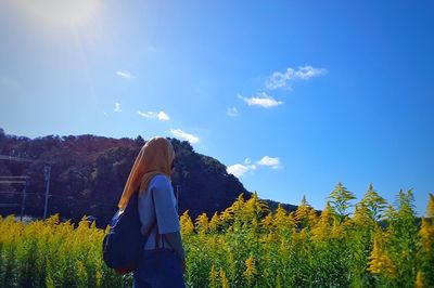 Rear view of woman standing on field against sky