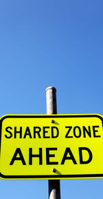 Low angle view of information sign against blue sky