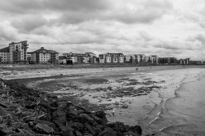 Scenic view of beach by buildings against sky