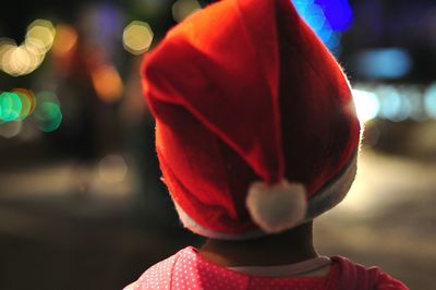 Close-up of person wearing santa hat against illuminated lights