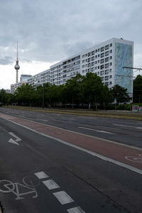 Road sign by buildings against sky in city