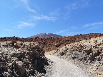 Scenic view of road by mountains against sky