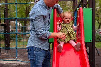 Father playing with baby girl on toboggan