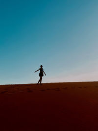 Full length of woman standing on sand dune against sky