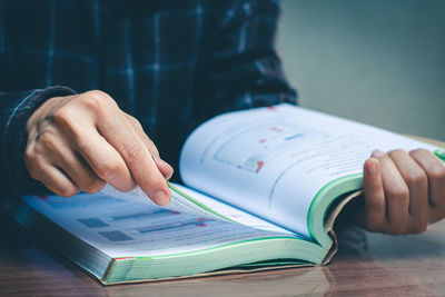 Close-up of man holding book on table