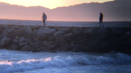 Silhouette man standing on beach against sky during sunset