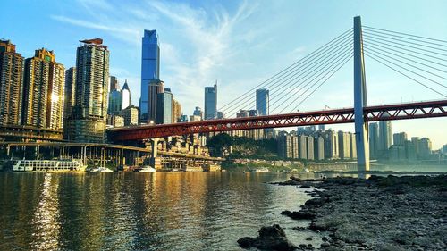 Low angle view of bridge over river and buildings against sky