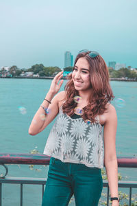 Beautiful young woman standing against sea