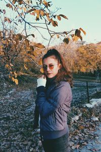 Portrait of smiling young woman standing against trees during winter