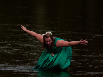 Midsection of woman with arms raised in lake