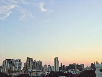 Modern buildings in city against sky during sunset