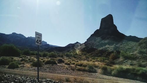 Road sign on landscape against sky