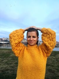 Portrait of smiling young woman in sweater against sky