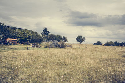 Trees on field against cloudy sky