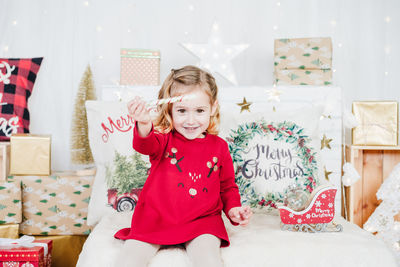 Cute little girl wearing red christmas dress at home over christmas decoration. holiday concept