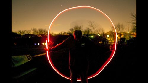 Rear view of man standing against sky at night
