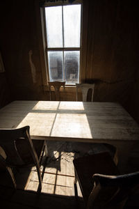 Empty chairs and table against window