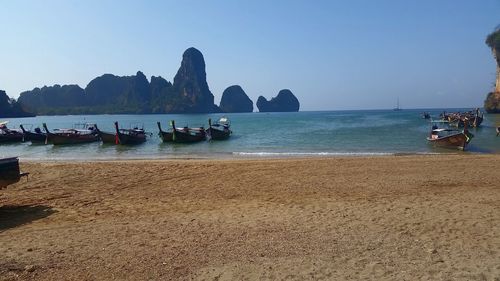 Boats moored in sea against clear sky