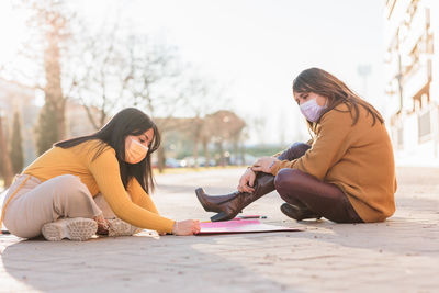 Females wearing mask writing on banner outdoors