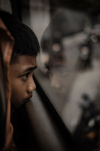 Close-up of boy looking through window