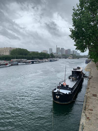 Boats in river by buildings in city against sky