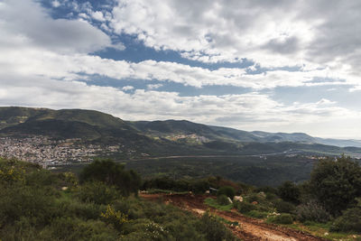 View of a mountain range and a green valley in the morning at sunrise, against a dramatic background 