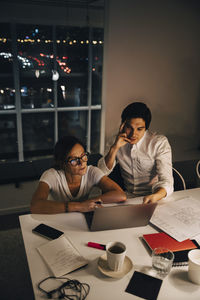 High angle view of female and male entrepreneurs sitting at desk during late night meeting in office