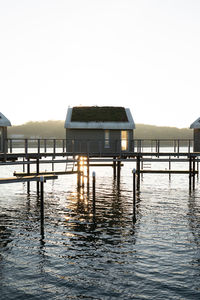 Stilt houses over lake against clear sky