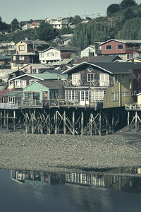 Bridge over river by buildings against sky