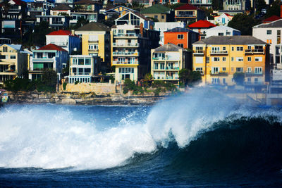 Close-up of waves on sea against city