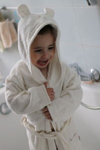 Cute boy wearing bathrobe while standing in bathroom at home