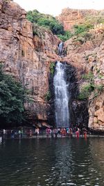 Group of people on rock against waterfall