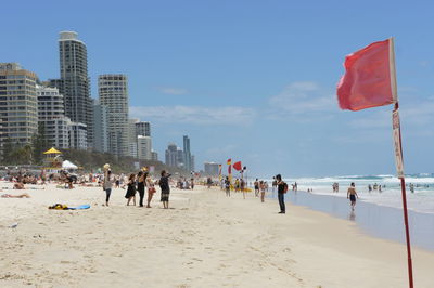 People at beach against sky in city