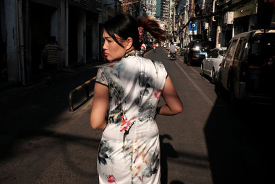 Woman looking away while standing on road in city