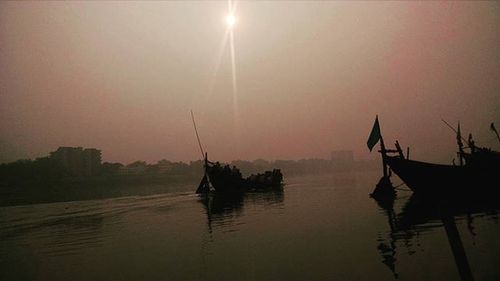 Boats in river at sunset