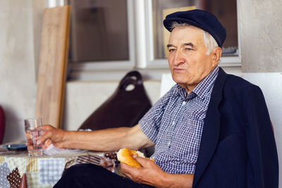 Midsection of man drinking glass while sitting at home