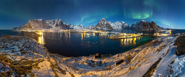 Panoramic view of lake by snowcapped mountains against sky at night