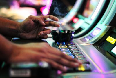 Close-up of hands playing slot machine