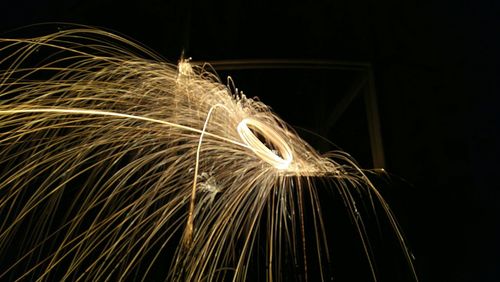 Low angle view of burning wire wool at window during night