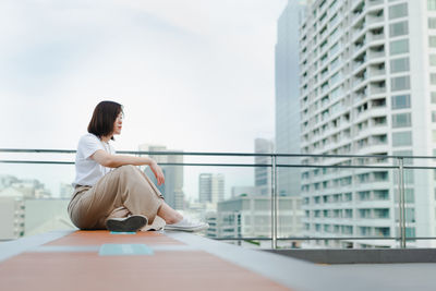 Solo asian woman sit and breatheduring outdoor break and relax at rooftop with city background