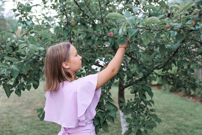 Side view of young woman standing against plants